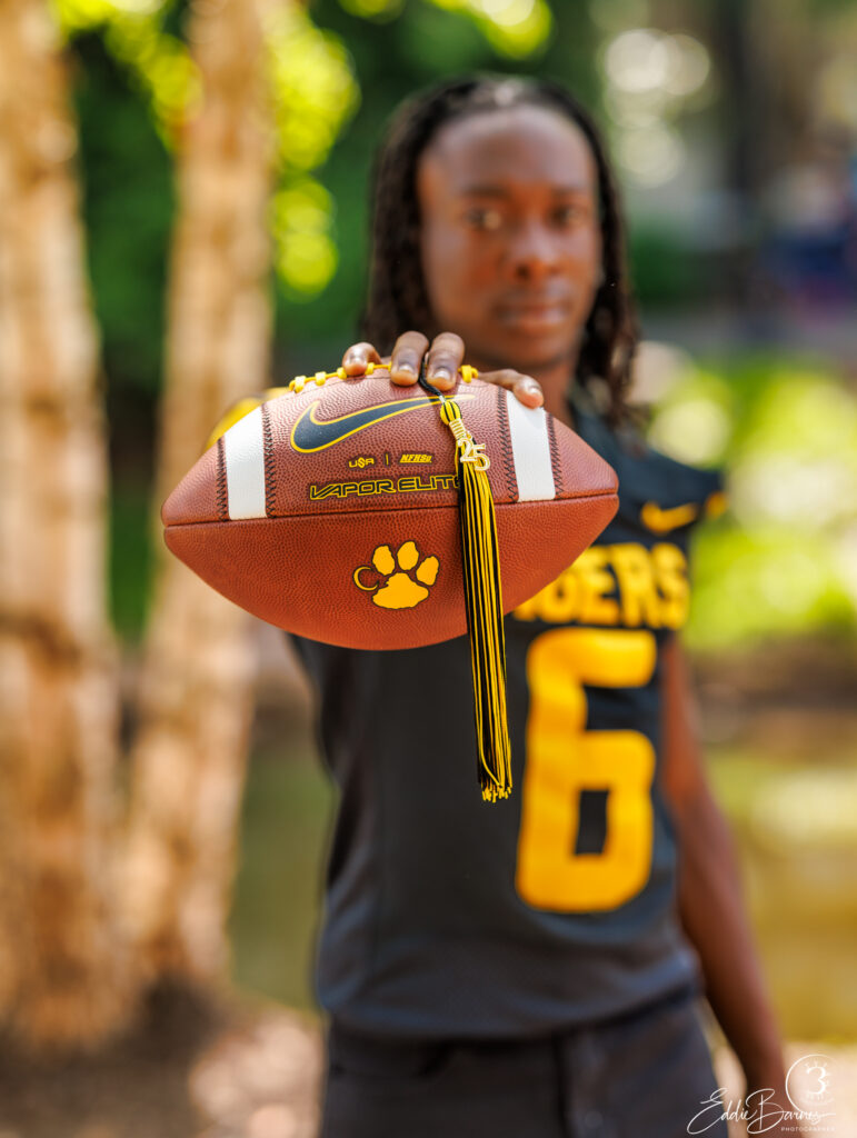 Young male graduate with football at Falls Park