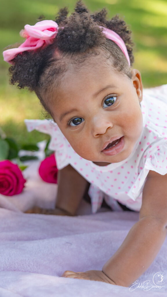 Close-up first birthday portrait of baby girl with roses during luxury portrait photography session in Greenville SC.