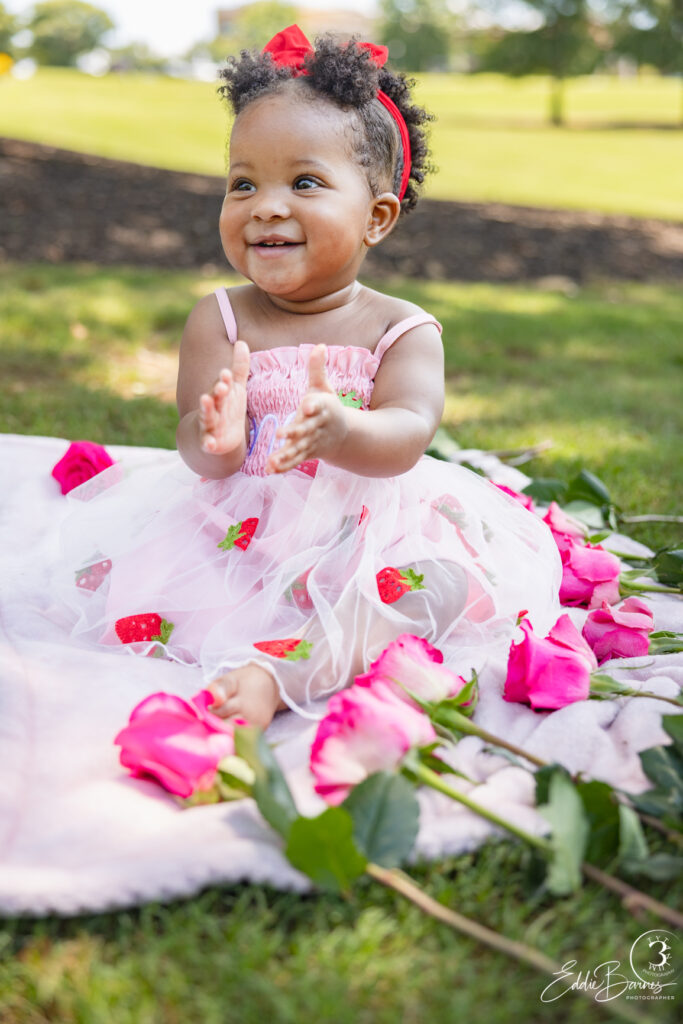 Baby girl clapping hands with pink roses during luxury portrait photography birthday session in Greenville SC.