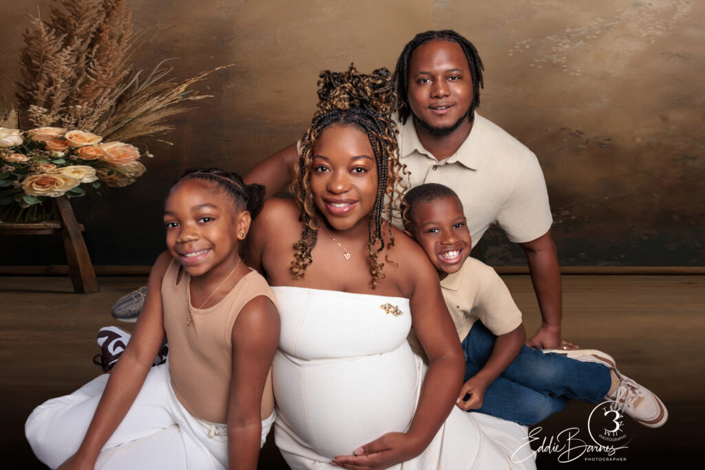 Family of four with mother expecting, children smiling and hugging during maternity session